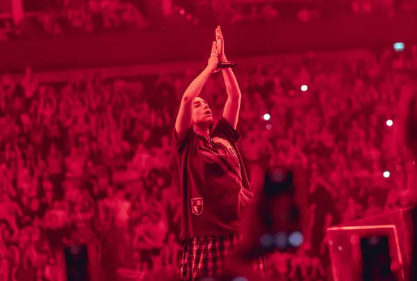 Billie Eilish, hands raised, in a red-lit arena, The O2, London, July 14, 2025