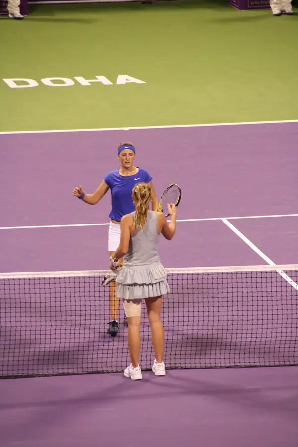 Caroline Wozniacki (back to camera, left thigh strapped) at the net after beating Victoria Azarenka, Doha, October 28, 2009 (not the Zvonareva match)