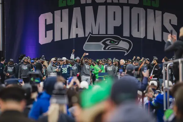 Seahawks players under a CHAMPIONS banner at the Super Bowl LX victory celebration, Seattle, February 11, 2026 (Derick Hall isn’t identifiable in it)