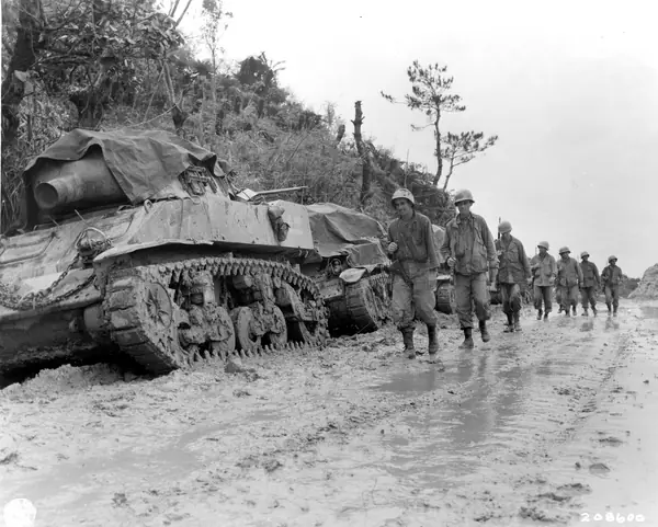 SC 208600 - Soldiers of the 77th Inf. Div. walk past mud-clogged tanks parked by the side of the road on Okinawa. 26 May, 1945
