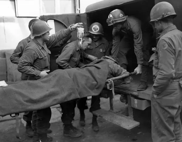 Medics carry an infantryman wounded by an anti-personnel mine into a 103rd Division aid station near Obermodern, France, February 27, 1945 (not Medicine Crow)