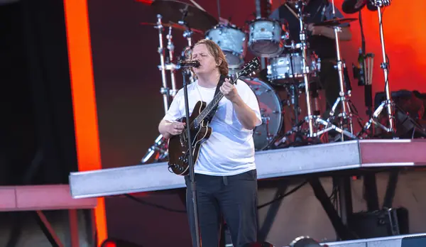 Lewis Capaldi singing with an electric guitar under red light, later in his set, Pyramid Stage, Glastonbury, June 24, 2023