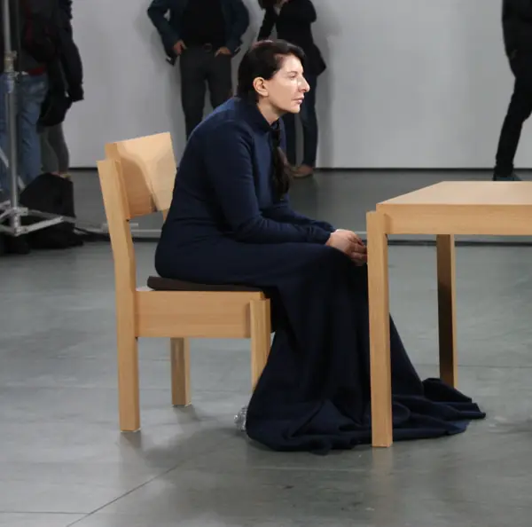 Marina Abramović in her navy dress at the table, MoMA, March 10, 2010, the day after the opening night (cropped)
