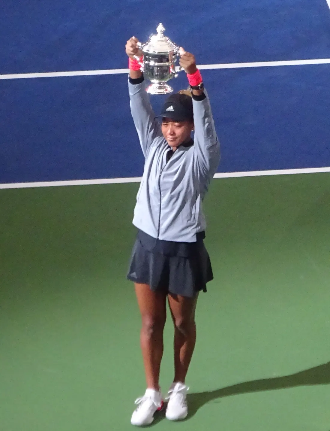 Naomi Osaka lifting the trophy at the 2018 US Open ceremony, Arthur Ashe Stadium, New York, September 8, 2018 (a spectator’s photo; the trophy lift, not the moment she cried)