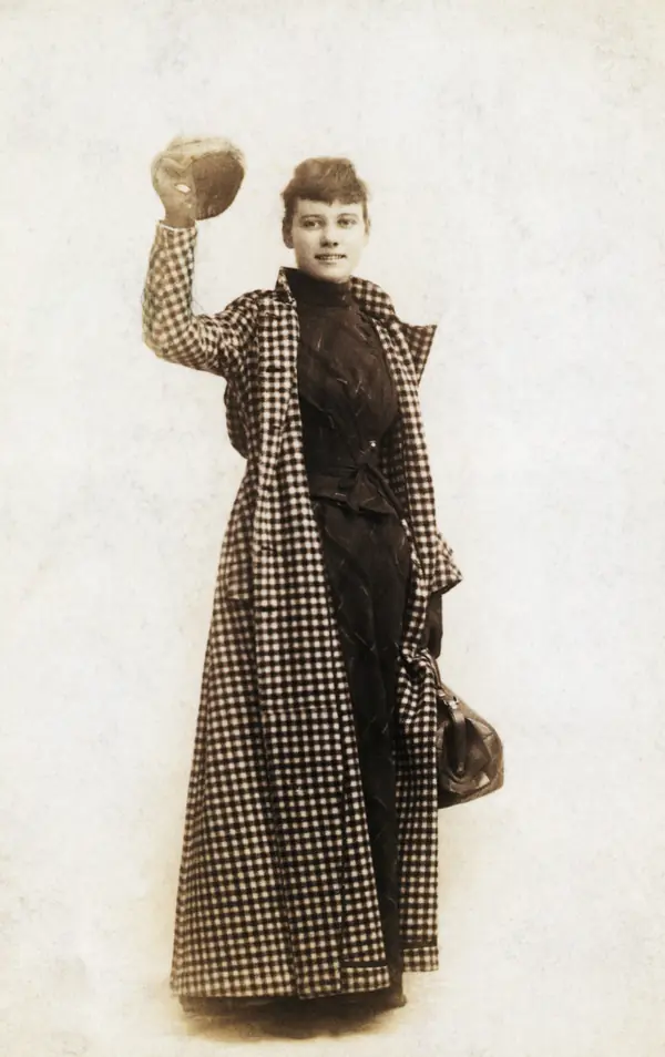 Nellie Bly in her traveling coat with her hand-bag, a publicity photo for her trip around the world, about 1889–90