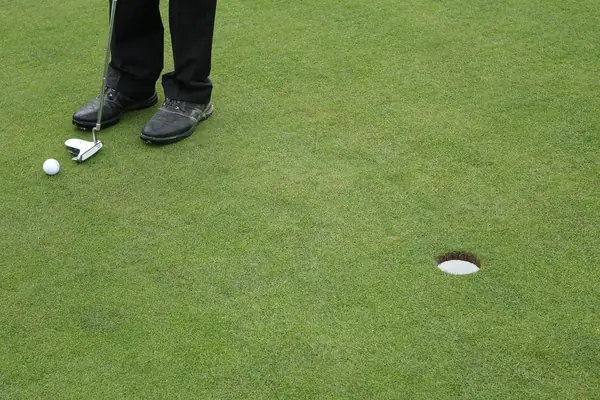 A stock photo of a golfer’s feet, a putter and a ball (not David Johnson)