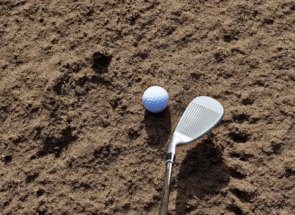 A stock photo of a golf ball and wedge in sand (not his ball or club)